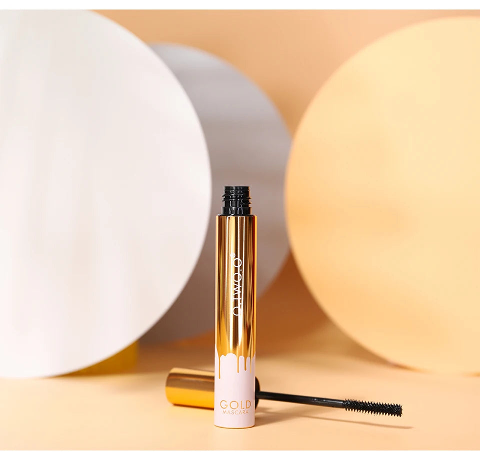 O.TWO.O 3D lengthening black mascara in a gold tube with applicator brush, isolated on a beige background.