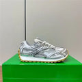 Luxury silver leather men's sneakers featuring a mesh panel design, white laces, and a rugged gum rubber outsole.