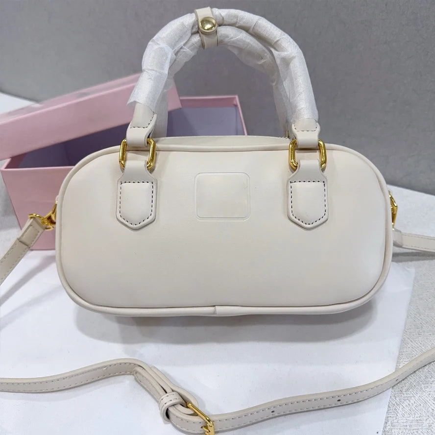 Cream luxury trunk handbag with gold hardware, top handle, and detachable shoulder strap in smooth leather style.