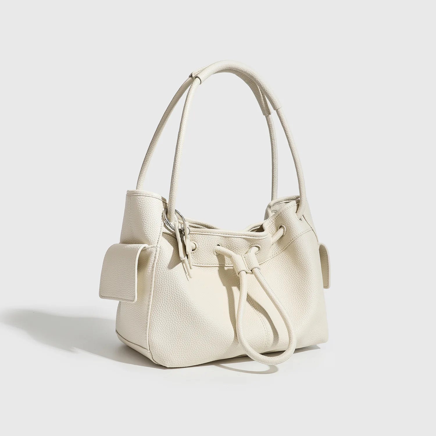 Off-white pebbled leather shoulder bag with drawstring closure, two straps, and side pockets for casual commuting.