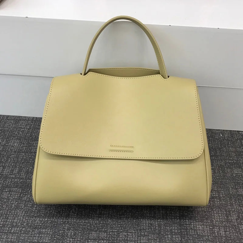 Minimalist yellow leather handbag in a Korean-style luxury design with a structured flap and top handle.
