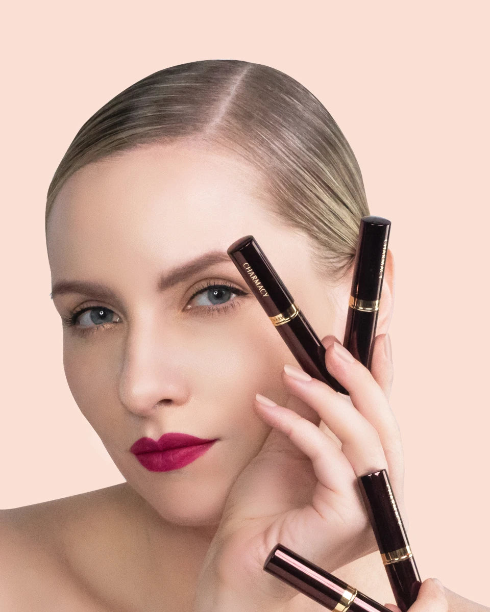 Model wearing Charmacy long-lasting matte velvet lipstick in deep magenta, holding elegant dark tubes of lip makeup.