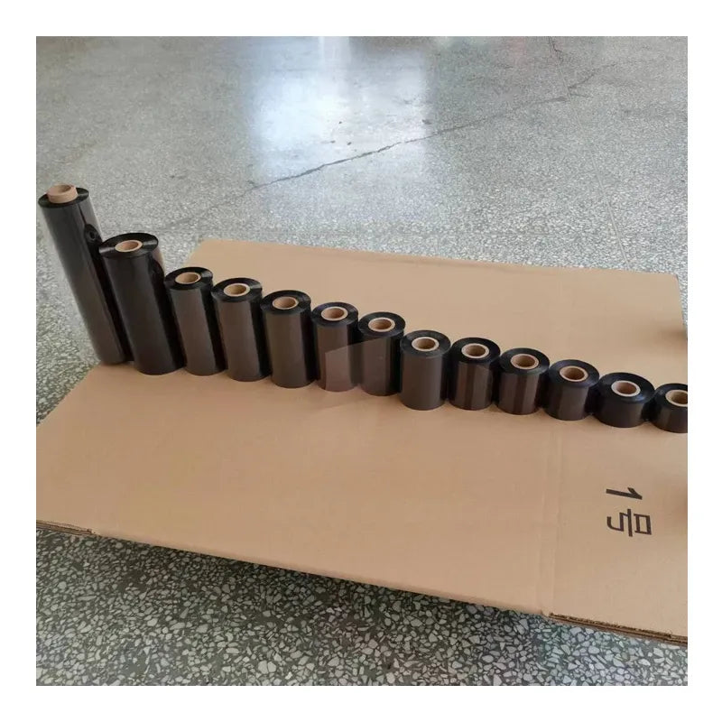 Multiple black thermal transfer ribbon rolls lined up on a cardboard sheet