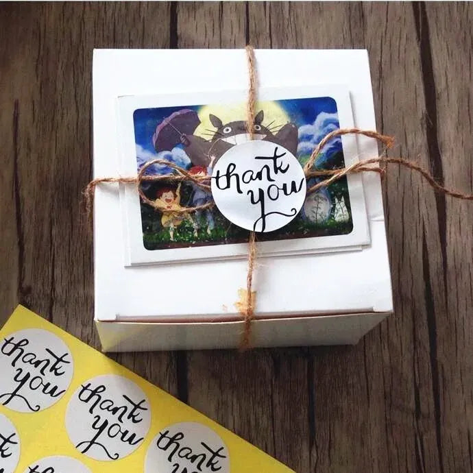 Small gift box wrapped with twine, featuring a round “thank you” adhesive sticker.
