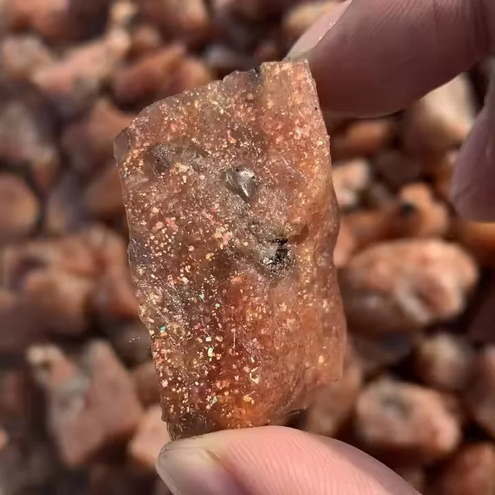 Rough golden-brown sunstone quartz crystal, held up for detail view