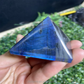 Blue labradorite flash pyramid crystal paperweight held in hand, glossy pointed top