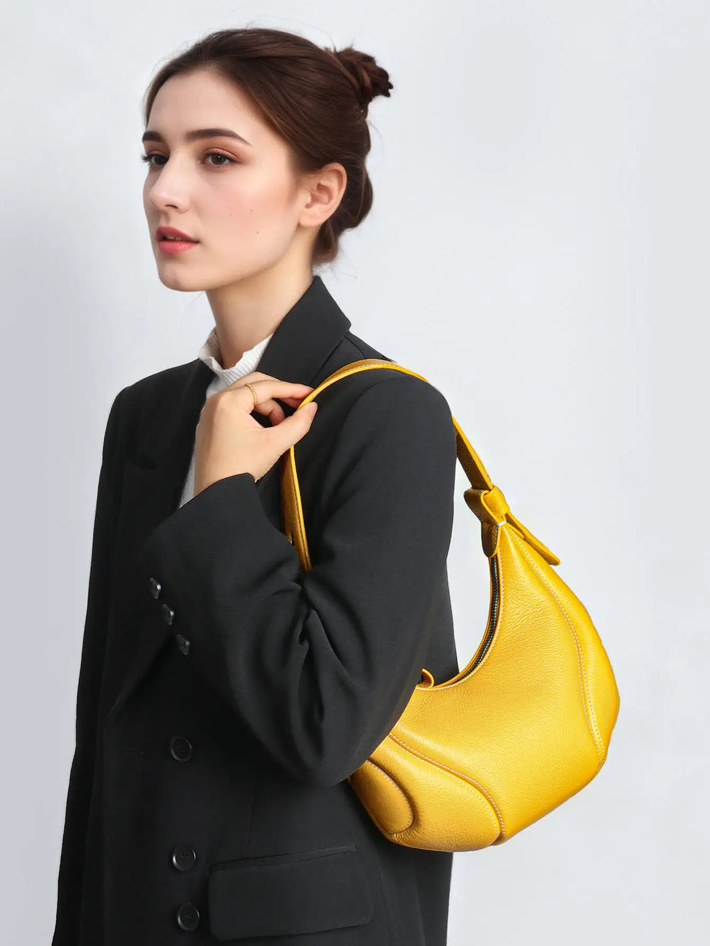 Yellow leather half-moon shoulder bag with a designer structured silhouette and zip closure.