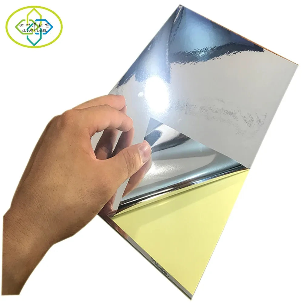 A4 glossy silver vinyl sticker paper sheet held up, reflective surface and light backing