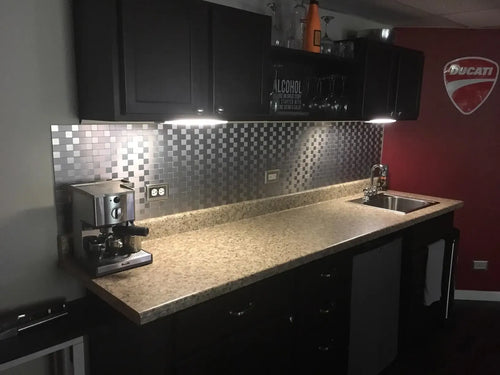 Stainless steel self-adhesive backsplash tiles with silver mosaic brick pattern behind sink
