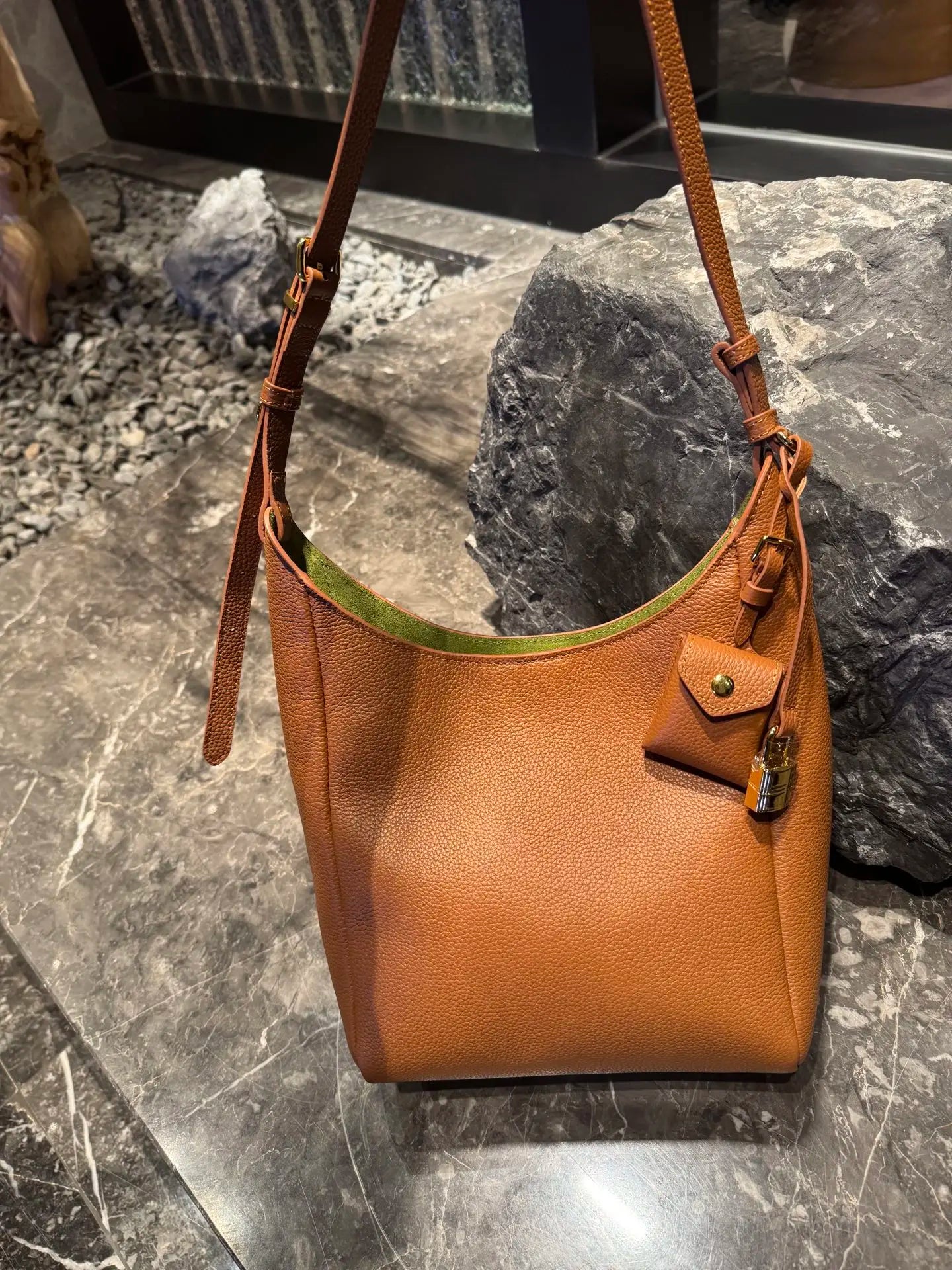 Brown genuine leather hobo shoulder bag with green interior, adjustable strap, mini pouch, and padlock charm.