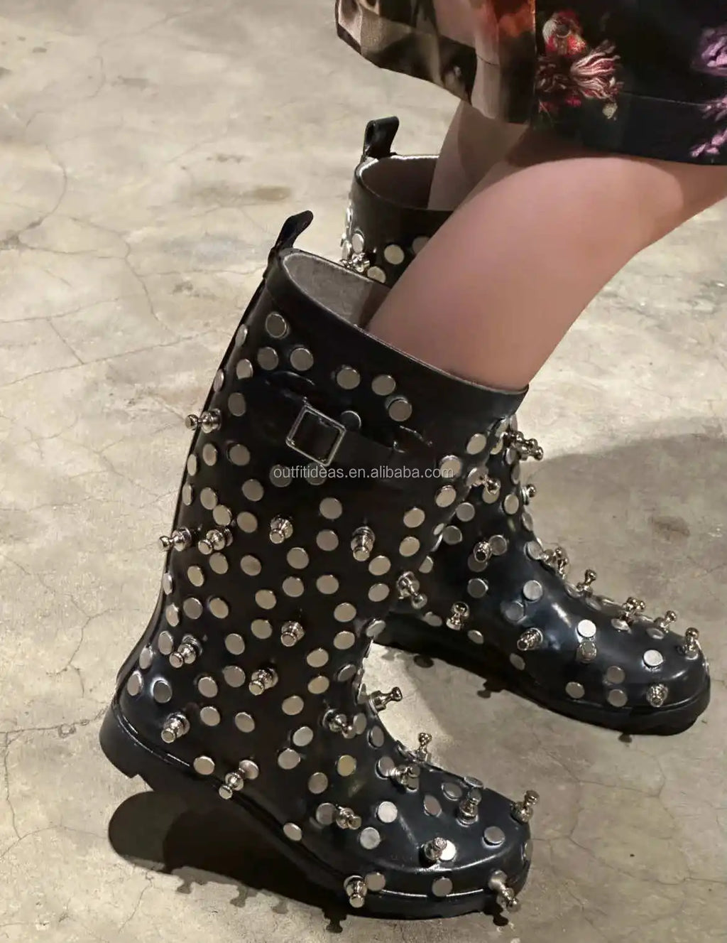 Black luxury boots featuring silver metal stud embellishments, buckled strap detail, and a chunky rubber lug sole.