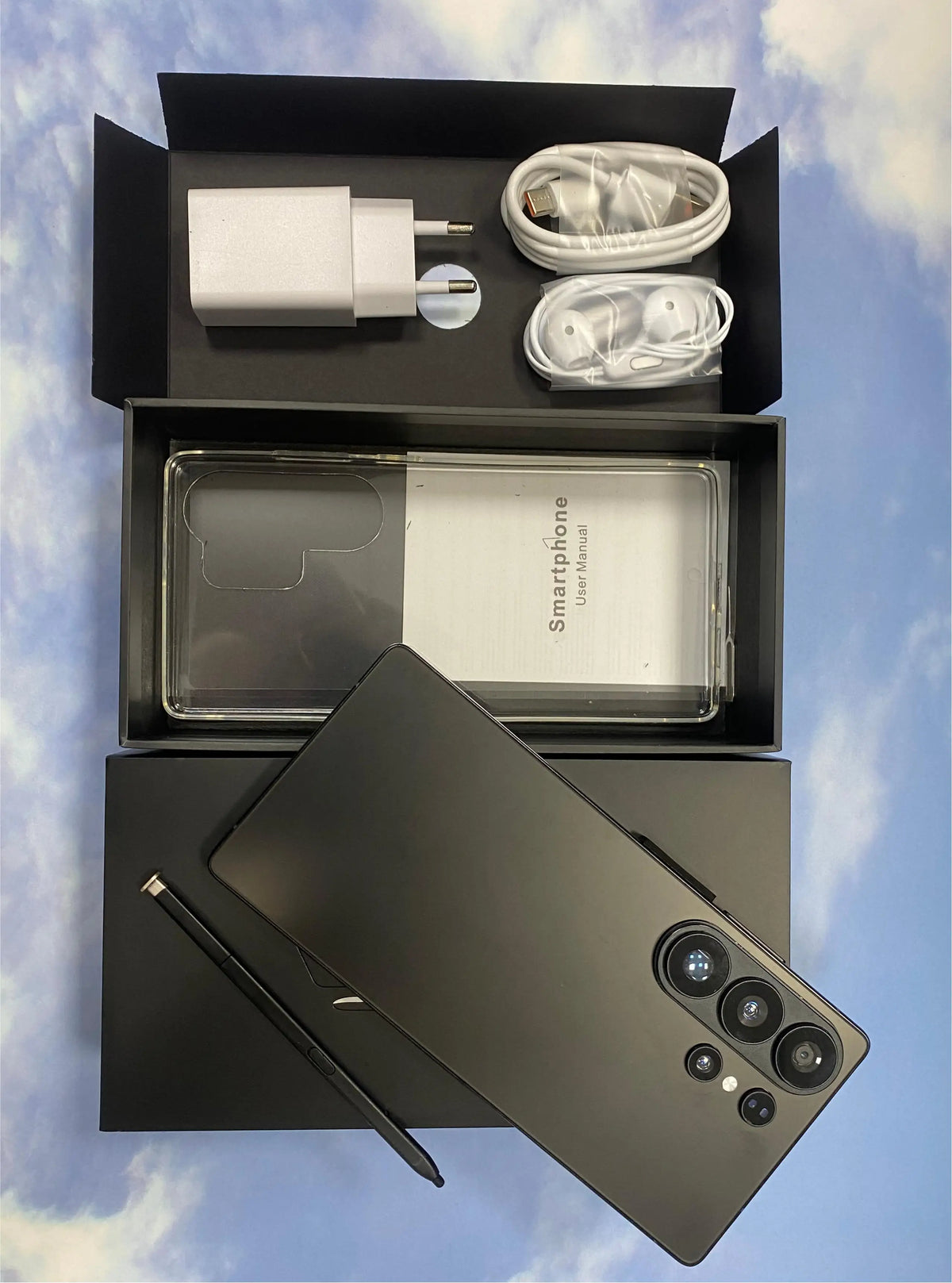 Dark-colored smartphone and built-in pen with accessories in open box packaging