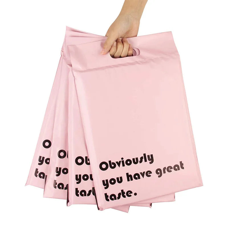 Pink poly mailer with built-in handle, stacked bags printed with “Obviously… taste”