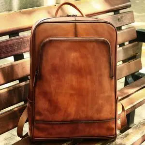 Tan genuine leather designer backpack with a structured vertical zip pocket and top handle.