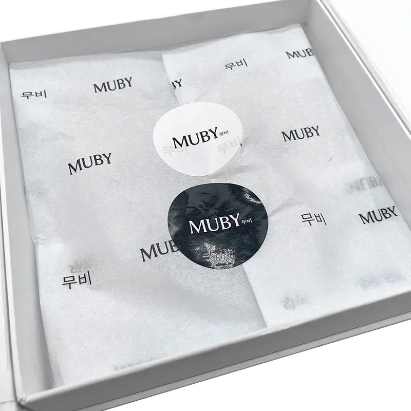 Round logo seal stickers in a box: white and dark circular labels with MUBY