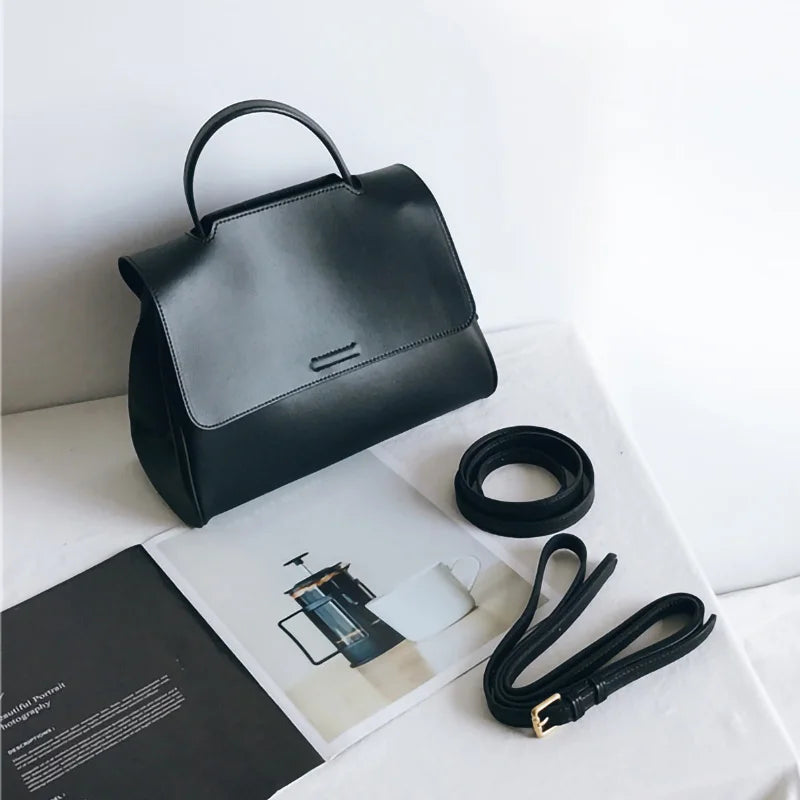 Minimalist black leather designer handbag with top handle and adjustable detachable shoulder strap. Korean style.