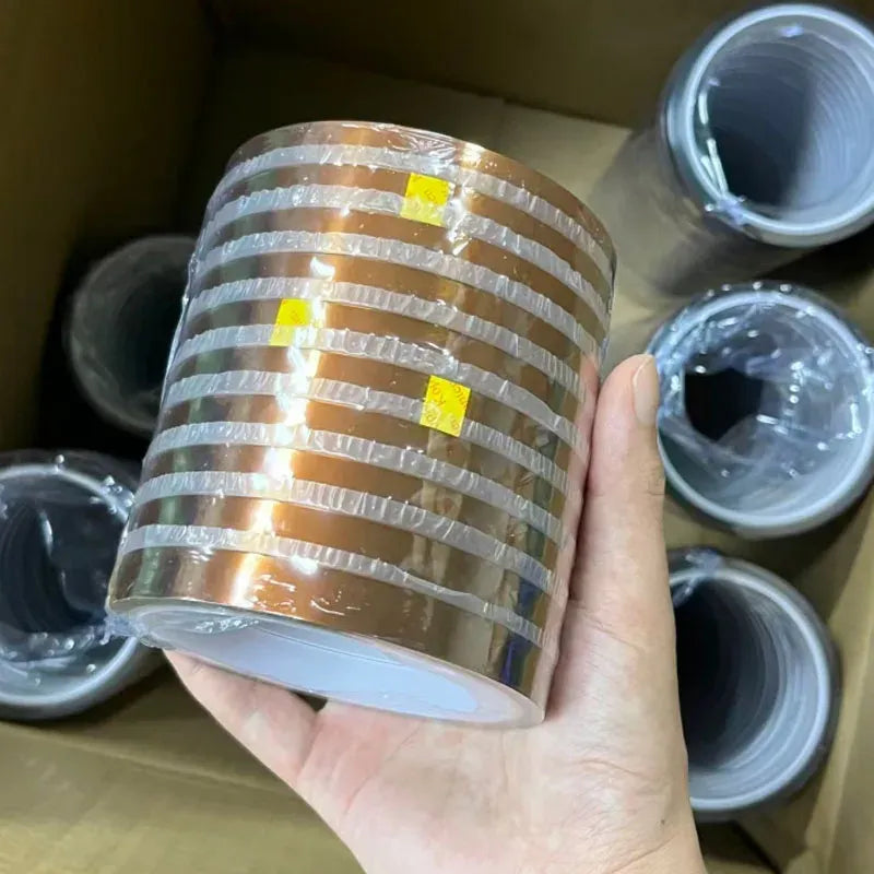 Amber polyimide tape roll held in hand, with multiple rolls in the box