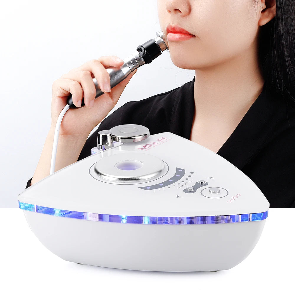 A woman uses a white, triangular RF skin-lifting device with a silver wand and blue LED light accents.