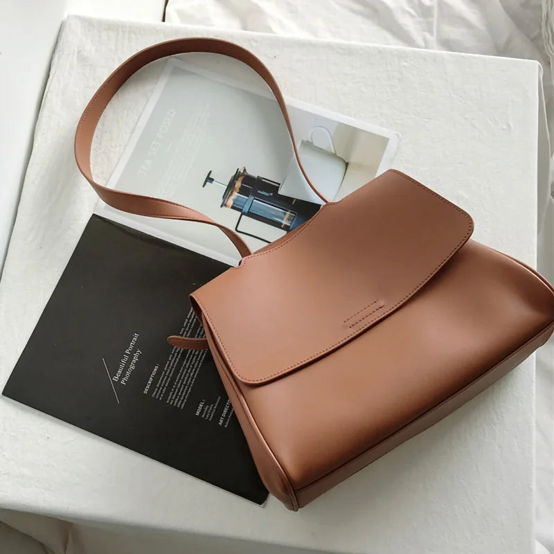 Minimalist tan leather designer handbag, Korean style messenger bag with flap closure and adjustable shoulder strap.