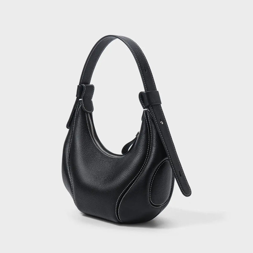 Black pebbled leather half-moon crossbody bag with white contrast stitching, shoulder strap, and zipper closure.