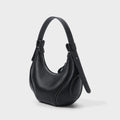Black pebbled leather half-moon crossbody bag with white contrast stitching, shoulder strap, and zipper closure.