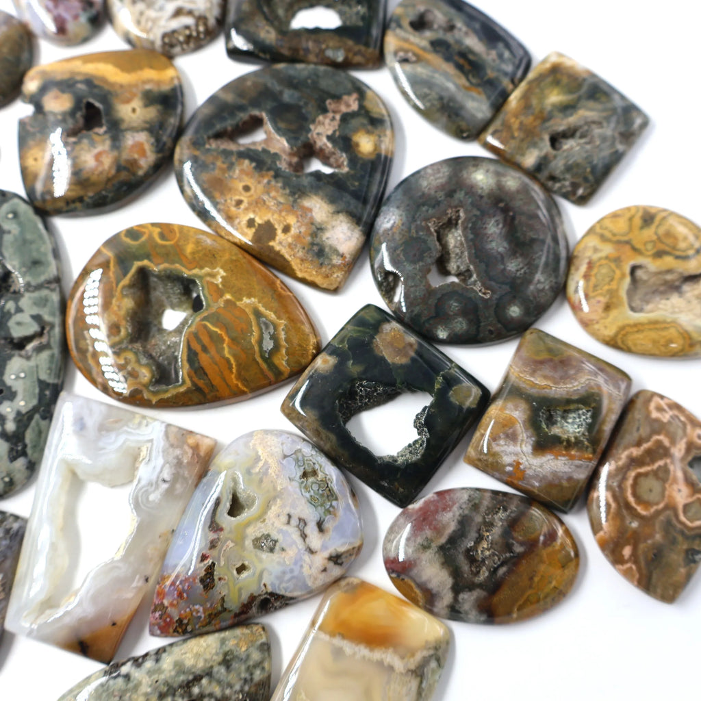 Close view of mixed ocean jasper druzy cabochons, oval and rectangle stones with dark speckles