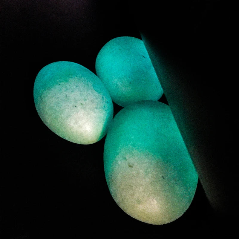 Glowing green oval luminous stones, smooth crystal pebbles on dark background