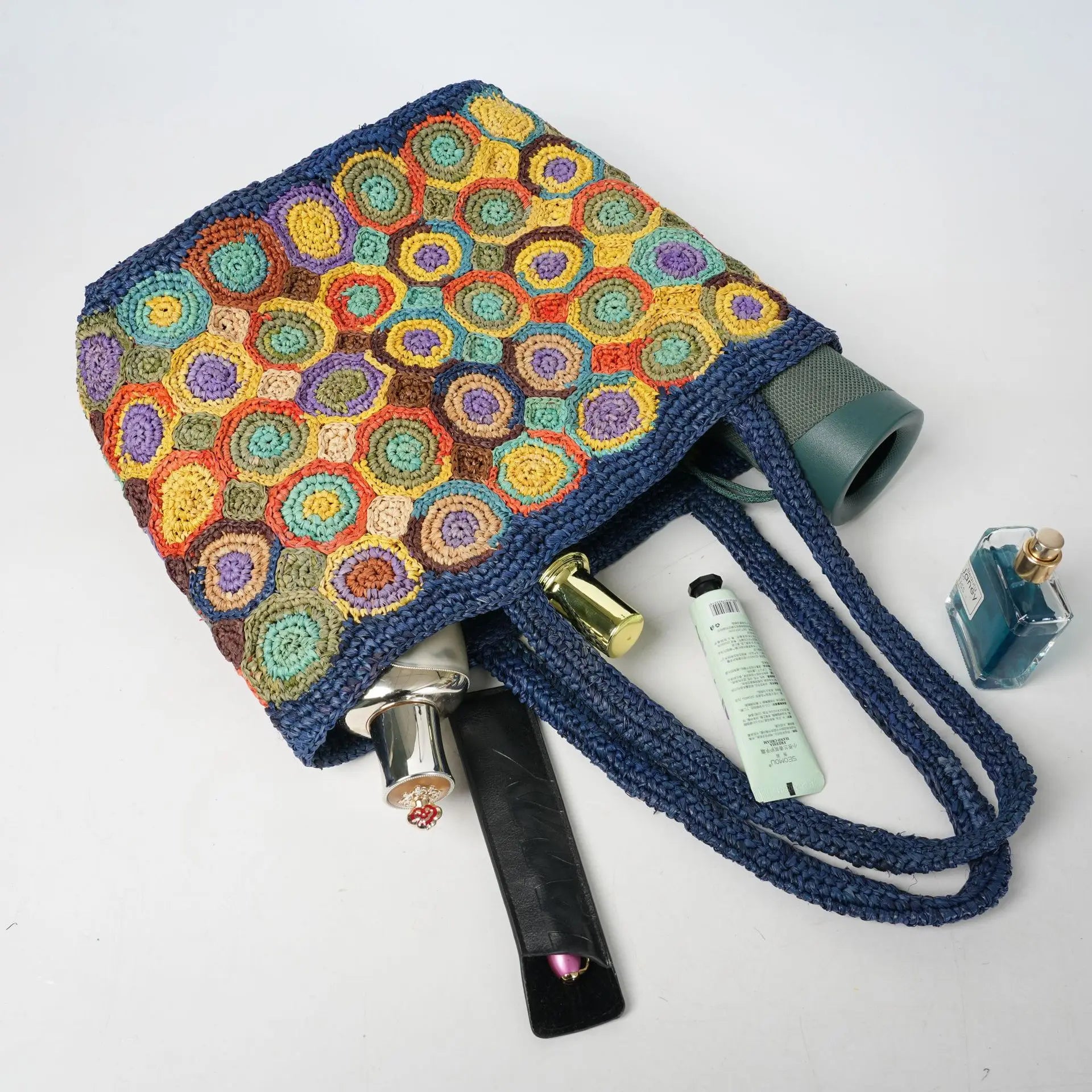 Multicolor woven crochet tote bag with navy blue handles, durable beach style design for summer fashion accessories.