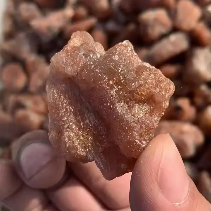 Raw golden sunstone quartz crystal, rough cut held in fingers