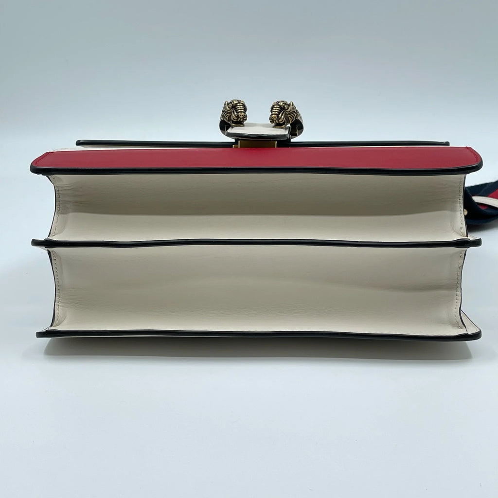 Designer handbag in white and red leather with metal tiger head clasp detail, perfect for luxury shoulder bag styles.