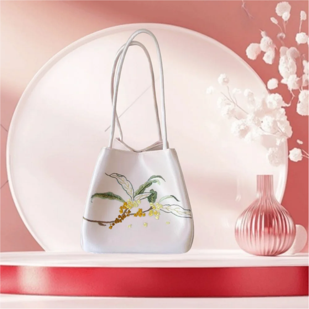 White handmade silk handbag featuring delicate floral Suzhou embroidery, elegant shoulder strap, designer style.