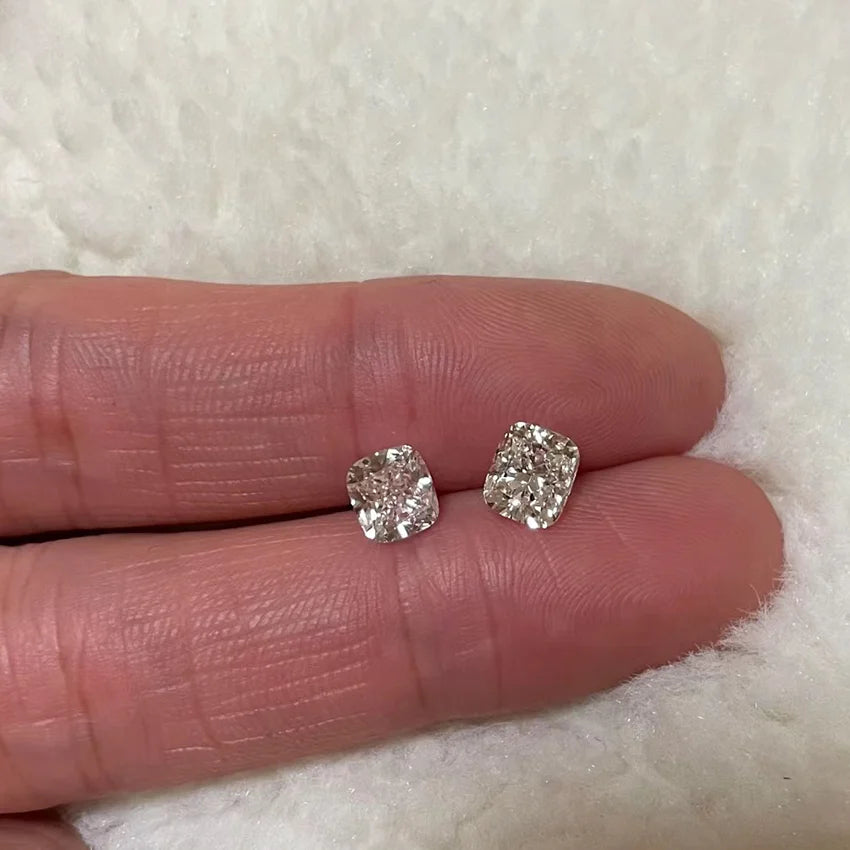 Two cushion-cut lab diamonds held in a hand