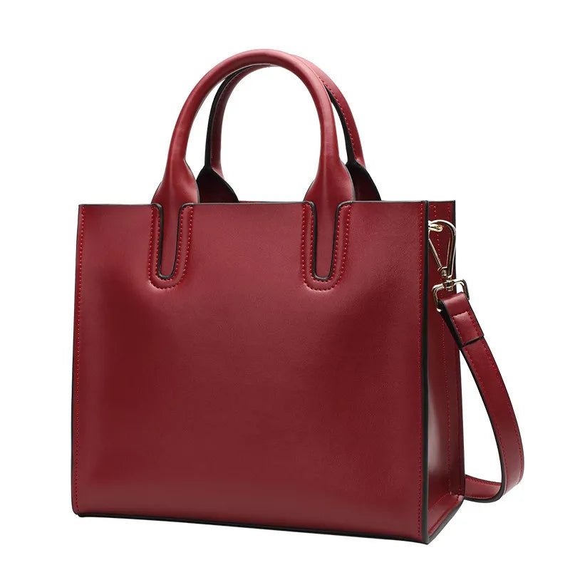 Red vintage-style genuine leather tote handbag with shoulder strap, casual structured messenger design for ladies.