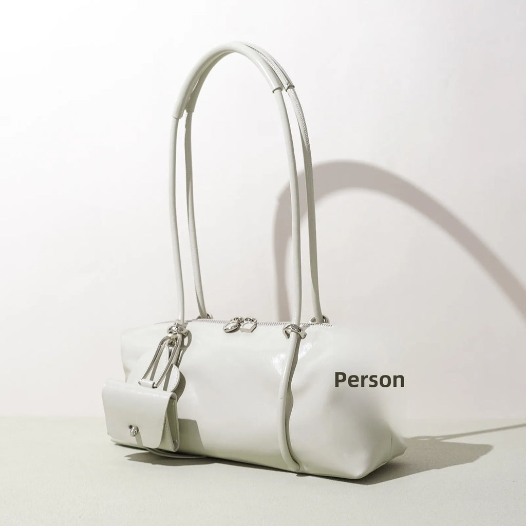 Minimalist white Boston underarm shoulder bag in luxe, smooth material with a matching mini pouch and zipper closure.