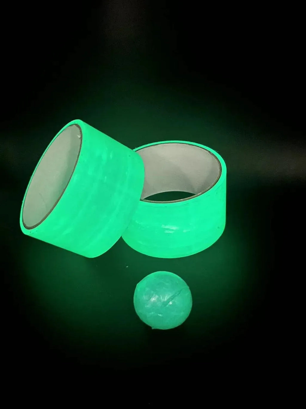 Two neon green glow tape rolls with a glowing green slime ball next to them