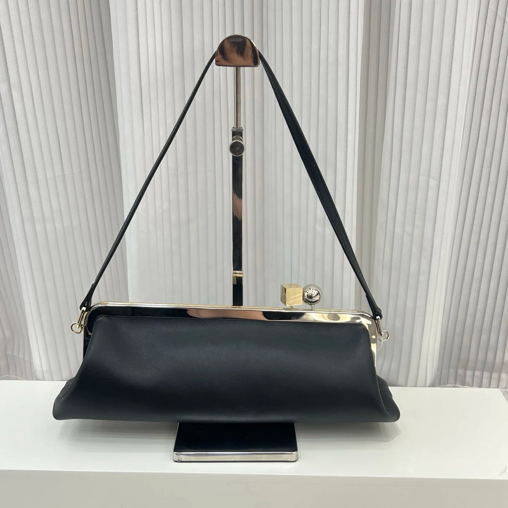 Black leather shoulder bag, designer handbag with gold metal frame, clip closure, and sleek rectangular silhouette.