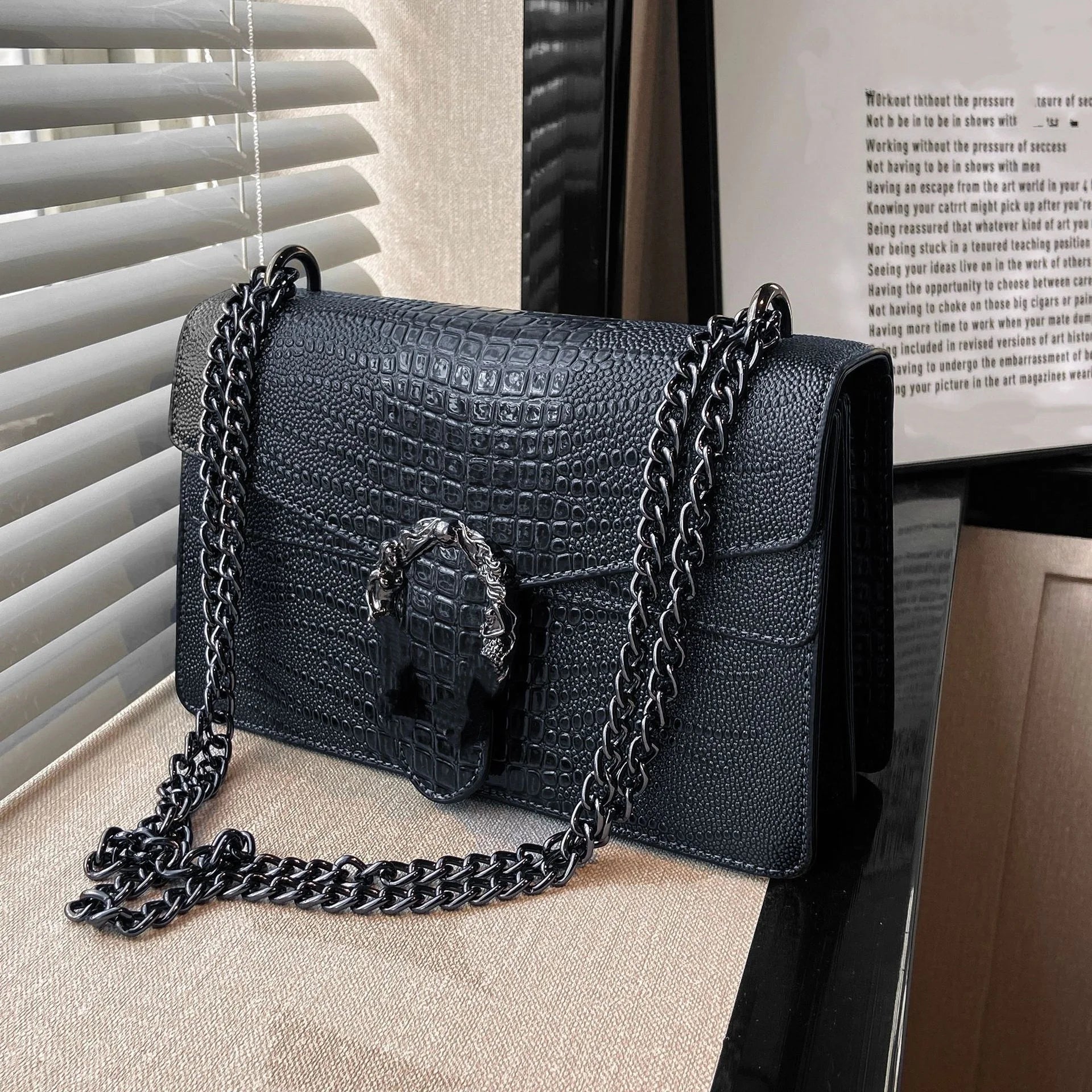 Black luxury trunk-style crossbody bag with crocodile texture, silver horseshoe buckle, and metallic chain strap.