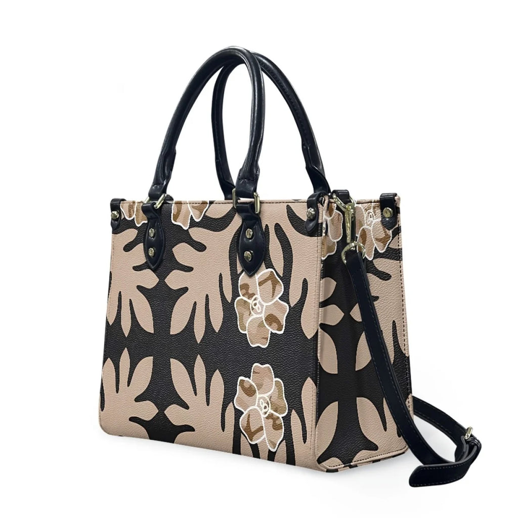 Luxury leather handbag featuring black and beige Polynesian tribal floral print with black handles and shoulder strap.
