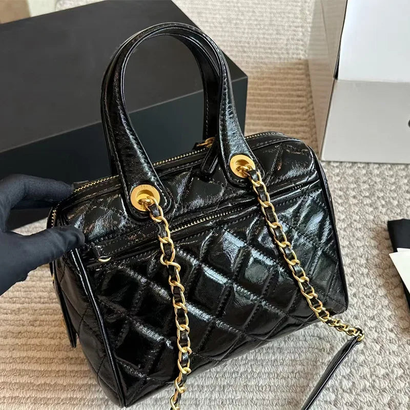 Black quilted patent leather barrel satchel with gold chain strap, luxury designer handbag.