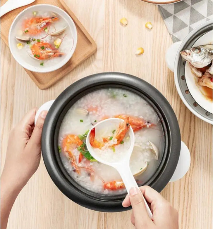 Mini electric rice cooker with open inner pot, shrimp soup being stirred with a ladle