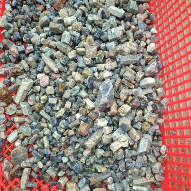 Heap of rough blue sapphire crystal raw gemstone chips in mesh