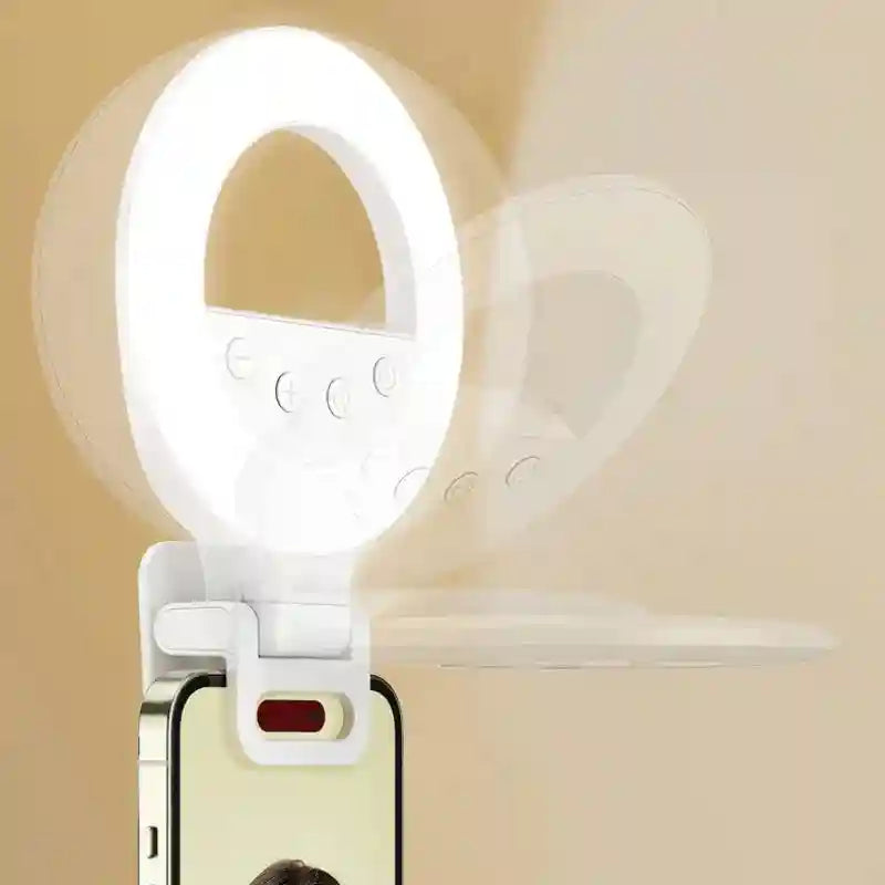 White circular clip-on LED ring light for mobile phones, featuring adjustable brightness buttons for selfie lighting.