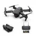Foldable black quadcopter drone with a camera, four propellers, and a matching remote controller with phone mount.