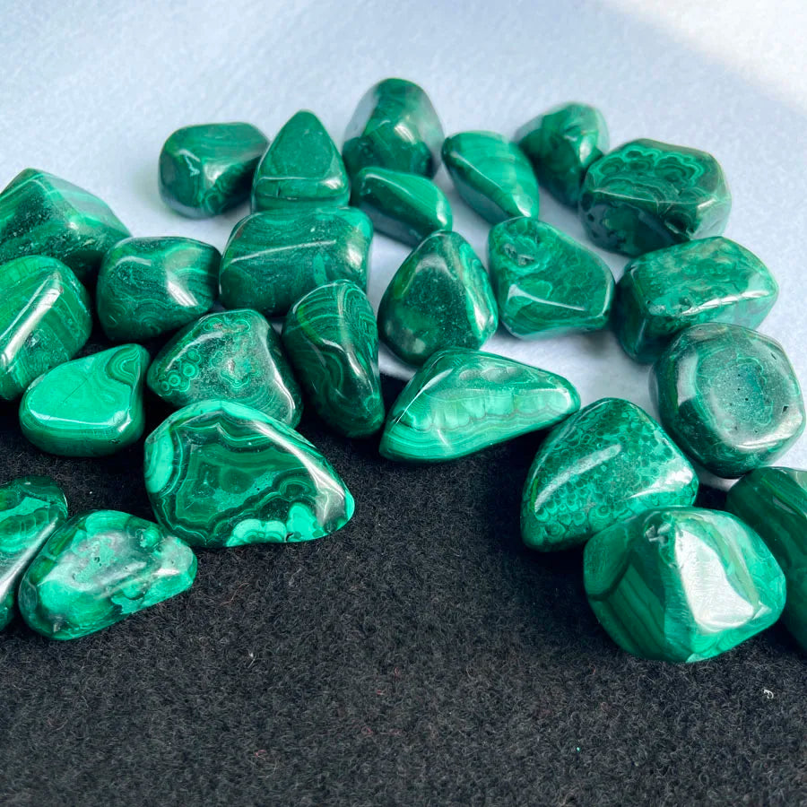 Assorted tumbled malachite stones, glossy dark green triangular and oval pieces
