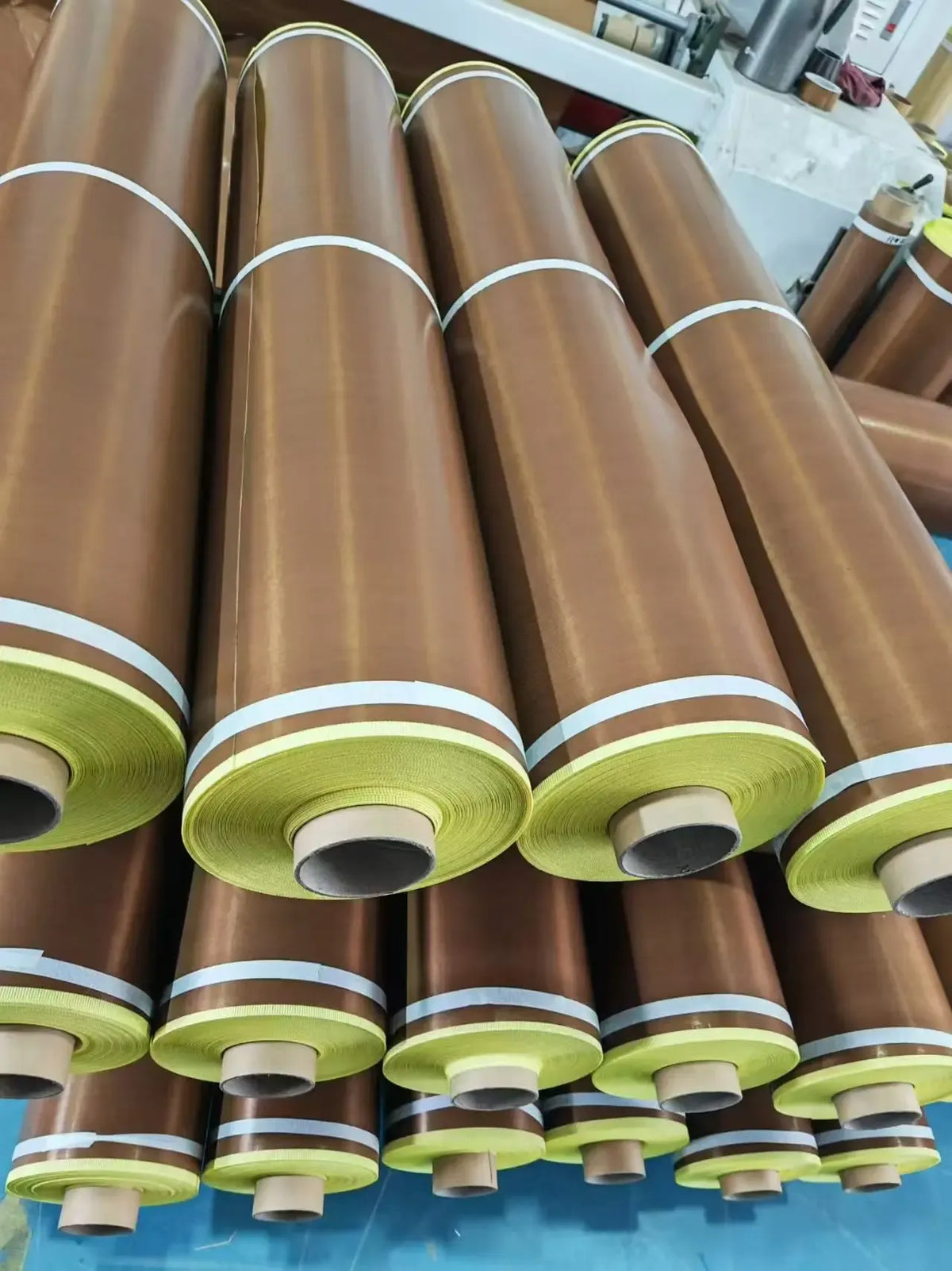 Bulk rolls of brown tape with green edge labels stacked tightly