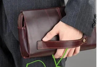 Dark brown genuine leather designer clutch bag with wrist strap, featuring a minimalist structured rectangular design.
