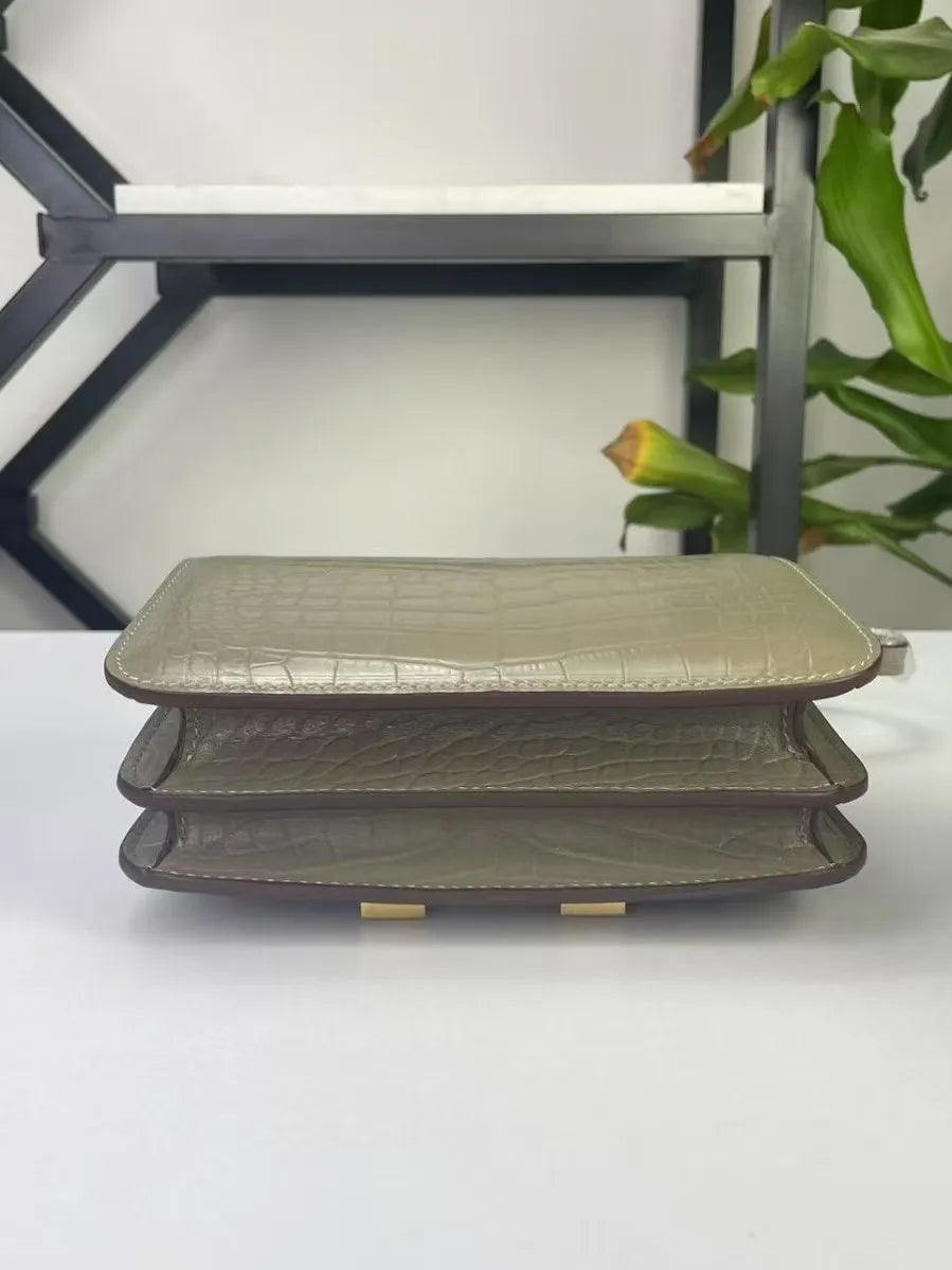 Grey alligator pattern genuine leather trunk style shoulder bag with multi-compartment design and gold-tone details.