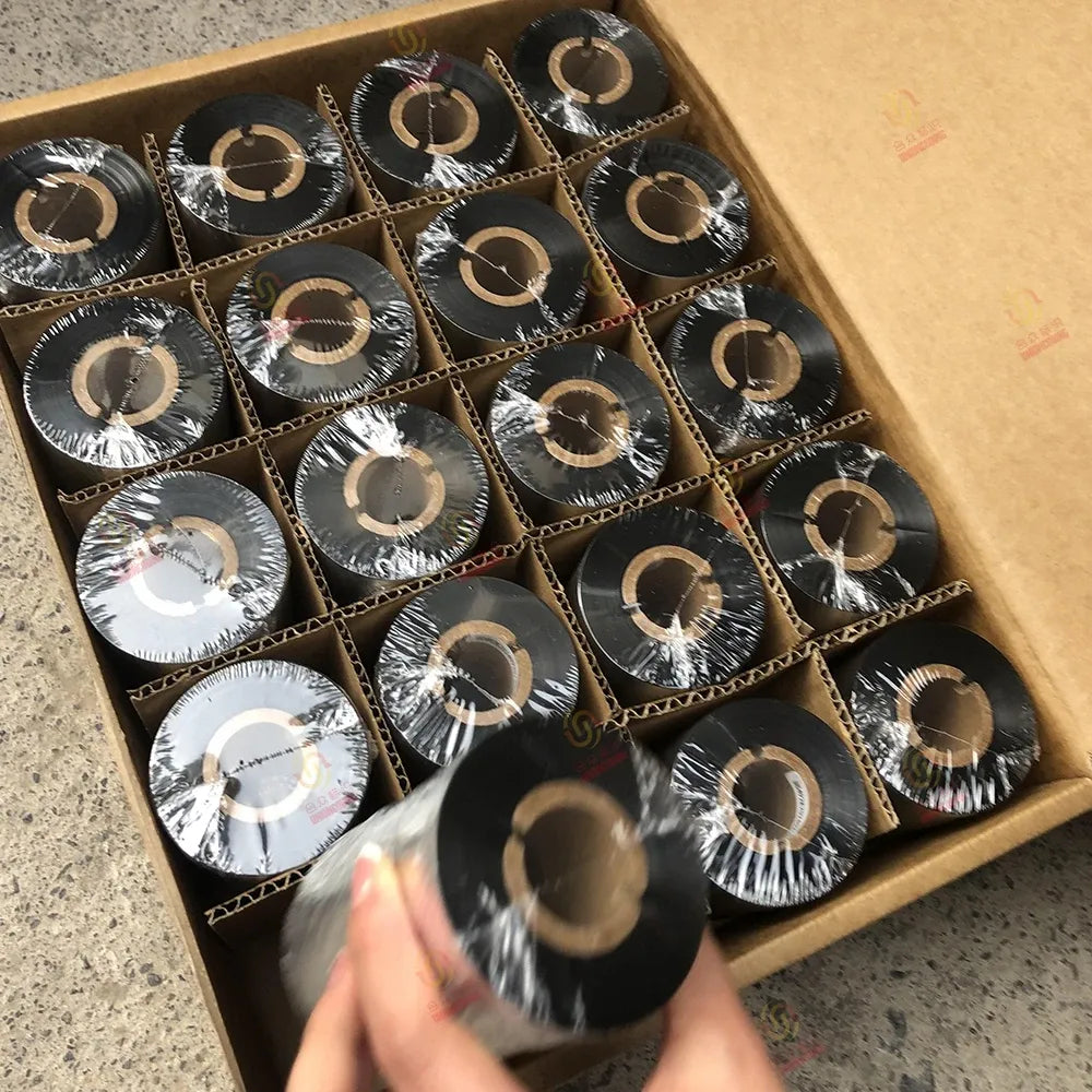 Black thermal barcode wax ribbon spools in a box, one roll held up by hand