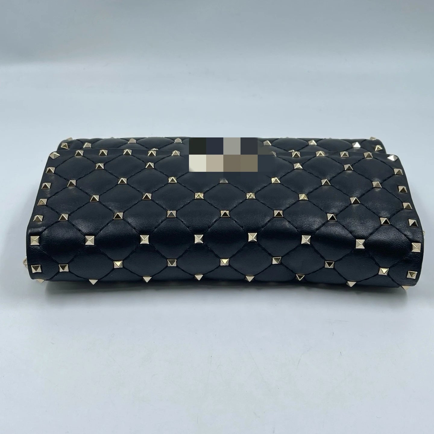 Luxury black quilted leather designer handbag with gold-tone pyramid rivets, rectangular shoulder bag style.