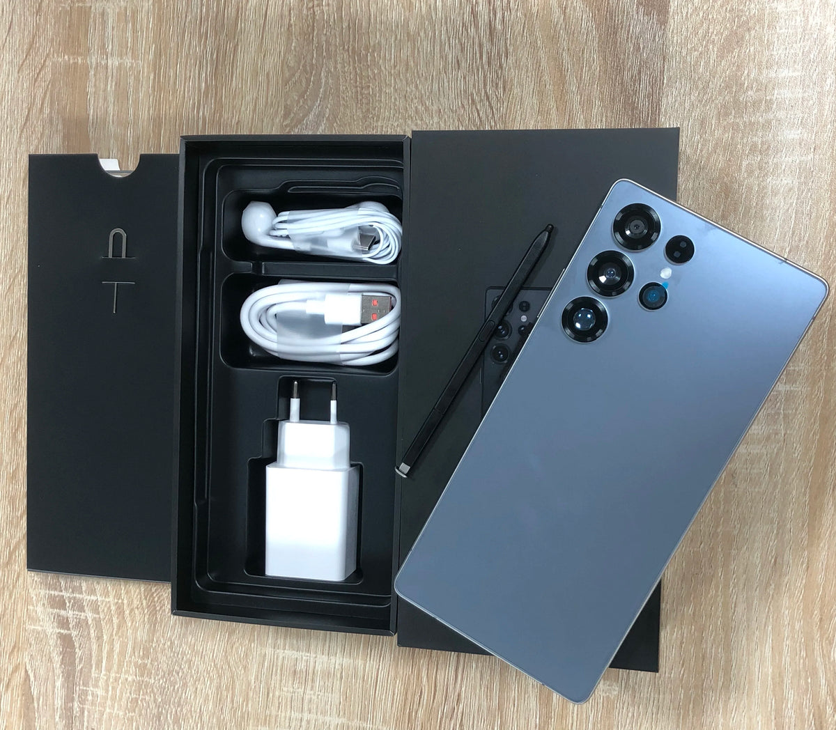 Blue smartphone with open retail box, charging cable, and wall adapter